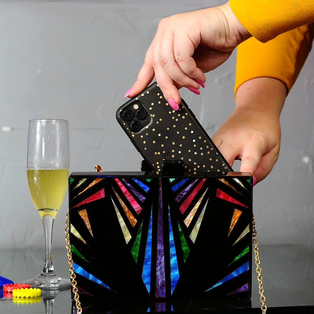 Model Placing Phone into Art Deco Rainbow & Black Cyndi Clutch