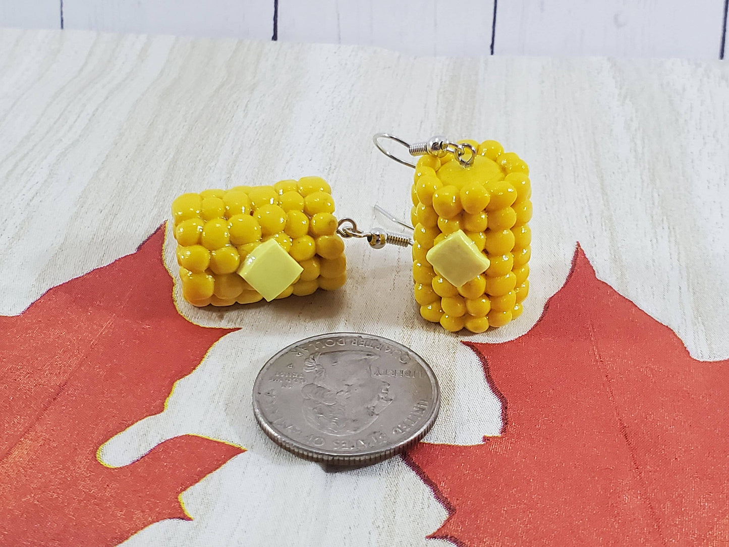 realistic buttered corn on the cob earrings next to quarter for size